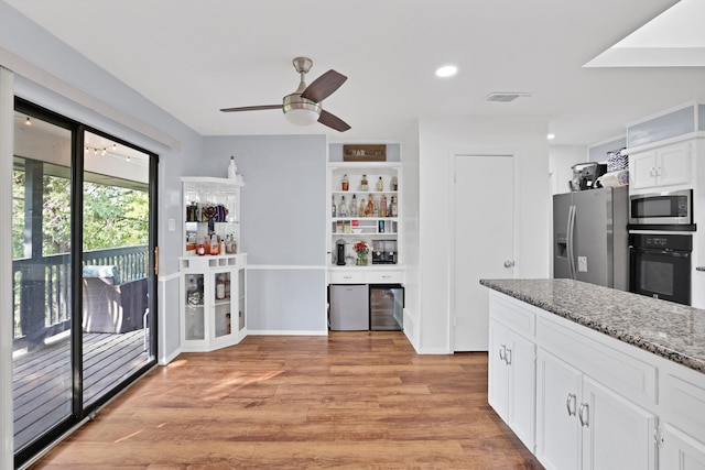 kitchen with dark stone counters, ceiling fan, light hardwood / wood-style floors, white cabinetry, and stainless steel appliances