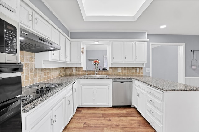 kitchen with black appliances, kitchen peninsula, sink, light wood-type flooring, and white cabinetry