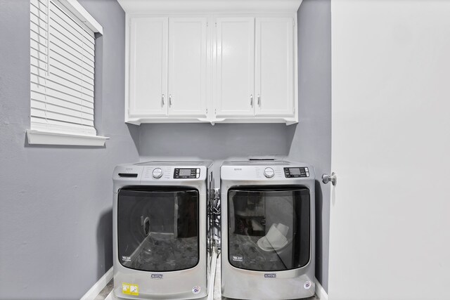 clothes washing area featuring cabinets and washer and clothes dryer