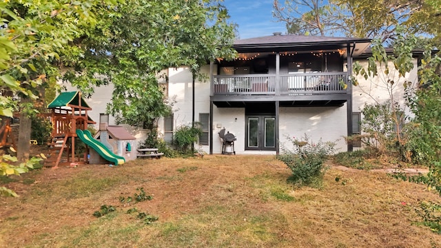 back of house with a balcony, a playground, and a yard