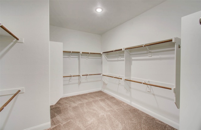 walk in closet with light carpet