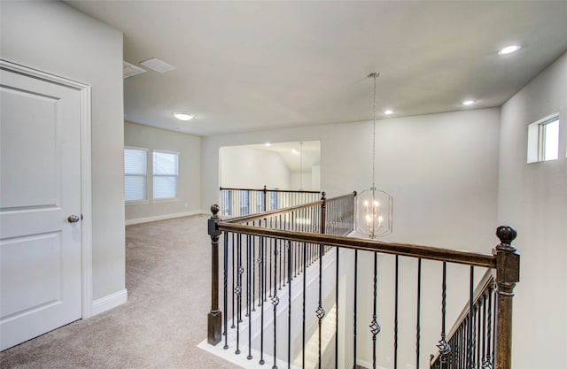 hall with light colored carpet and a chandelier