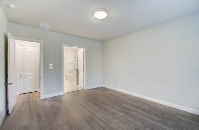 unfurnished bedroom featuring connected bathroom and hardwood / wood-style flooring