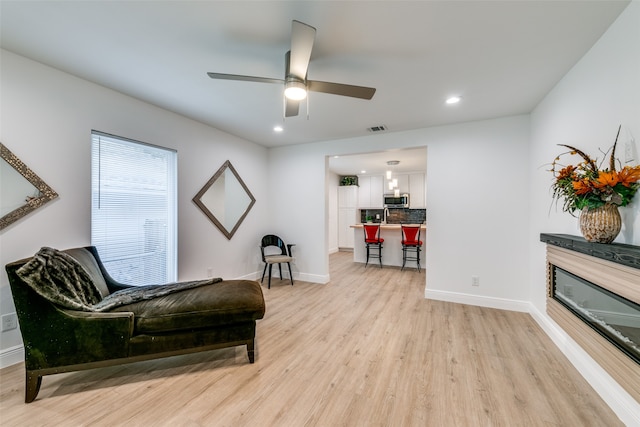 living area featuring light hardwood / wood-style floors and ceiling fan