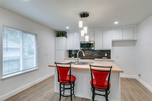 kitchen featuring a wealth of natural light, a center island with sink, and white cabinets