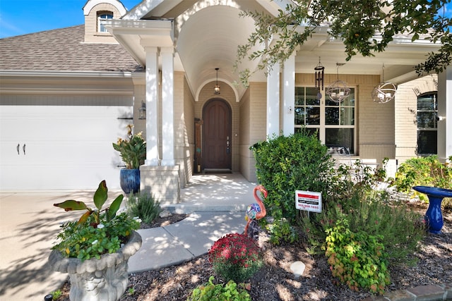 view of exterior entry featuring covered porch and a garage