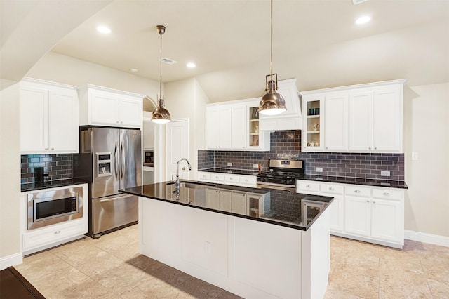 kitchen with white cabinetry, appliances with stainless steel finishes, decorative light fixtures, and a kitchen island with sink