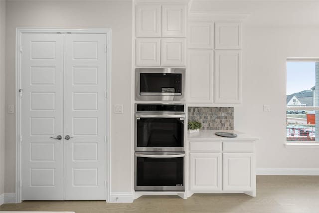 kitchen featuring white cabinetry, appliances with stainless steel finishes, a wealth of natural light, and light hardwood / wood-style floors