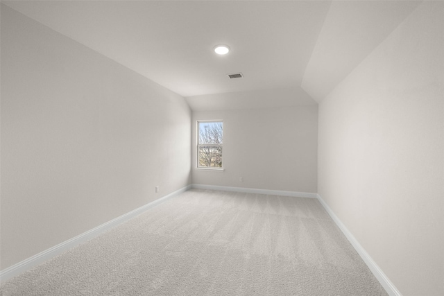 carpeted empty room with vaulted ceiling