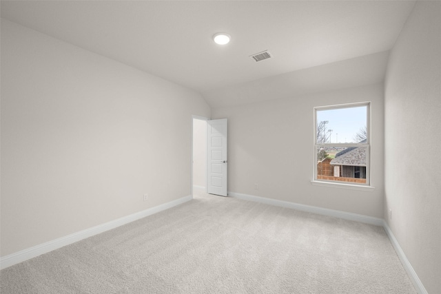 carpeted spare room with vaulted ceiling