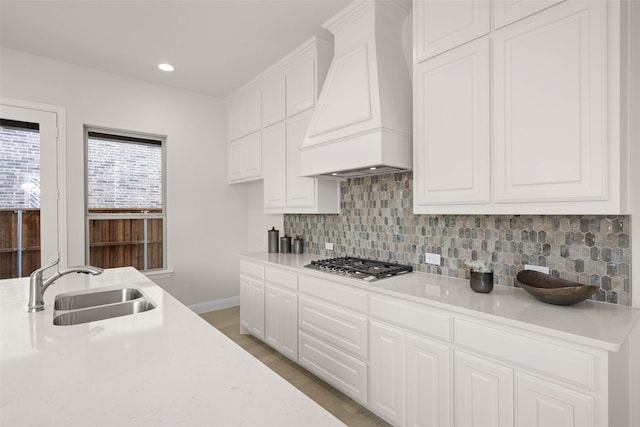 kitchen featuring sink, tasteful backsplash, white cabinets, custom exhaust hood, and stainless steel gas stovetop