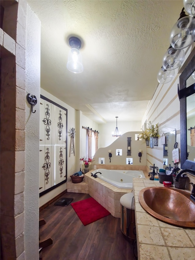 bathroom featuring vanity, hardwood / wood-style floors, a relaxing tiled tub, and a textured ceiling