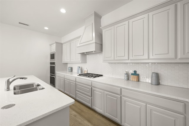 kitchen with visible vents, light wood-style flooring, custom range hood, stainless steel appliances, and a sink