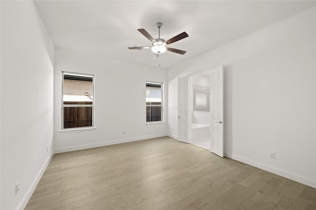 empty room with ceiling fan, light wood-style flooring, and baseboards