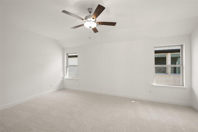 spare room with lofted ceiling, ceiling fan, baseboards, and light colored carpet