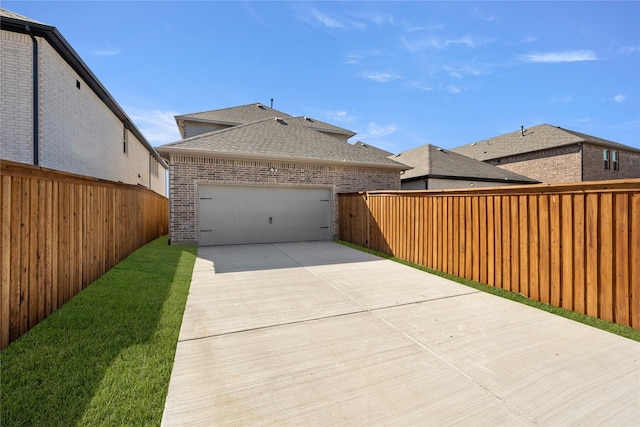 exterior space featuring a garage, a fenced backyard, and concrete driveway