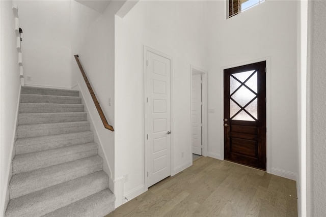 foyer featuring baseboards, visible vents, stairway, and wood finished floors