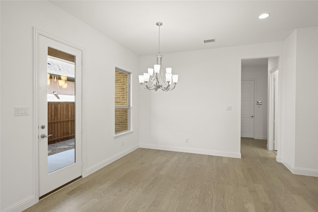 unfurnished room with baseboards, visible vents, light wood finished floors, and an inviting chandelier