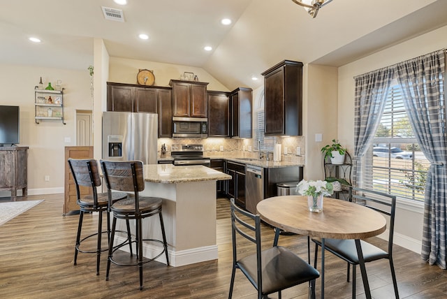 kitchen featuring light stone counters, a center island, stainless steel appliances, tasteful backsplash, and visible vents