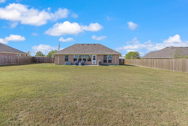 rear view of property with a yard, brick siding, a patio area, and a fenced backyard