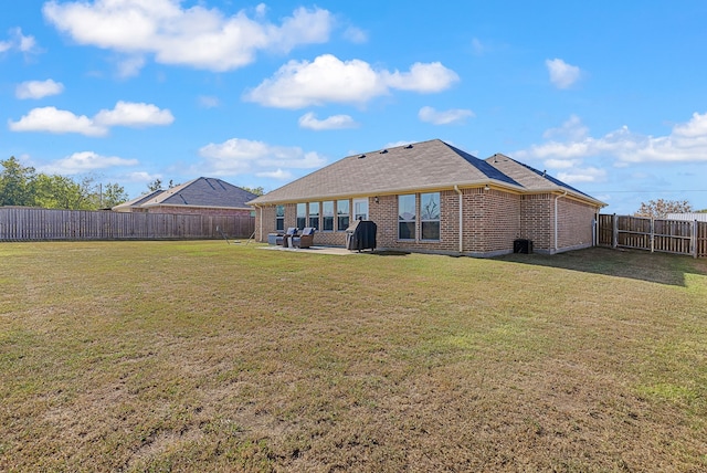 rear view of house with a patio area, a fenced backyard, a yard, and brick siding