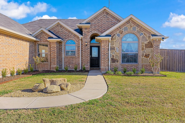 view of front of property featuring brick siding, a front lawn, and fence