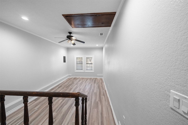 corridor with ornamental molding and light hardwood / wood-style floors