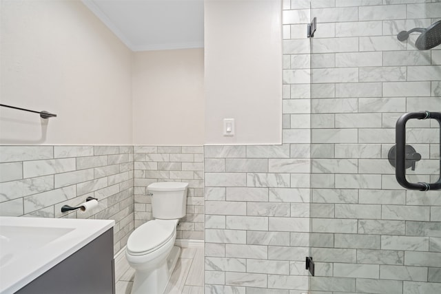 bathroom featuring toilet, crown molding, tile walls, vanity, and a shower with door