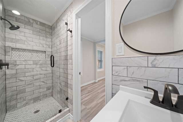 bathroom featuring sink, tile walls, wood-type flooring, ornamental molding, and a shower with shower door