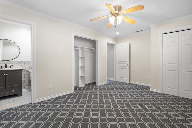 unfurnished bedroom with sink, ensuite bath, ceiling fan, ornamental molding, and two closets