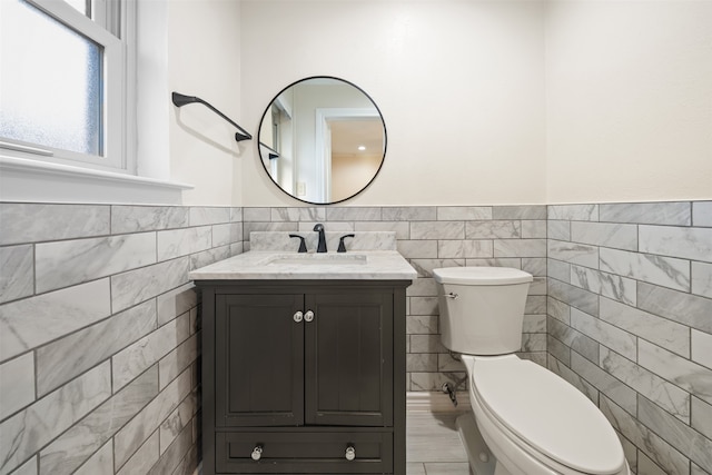 bathroom with vanity, tile walls, and toilet