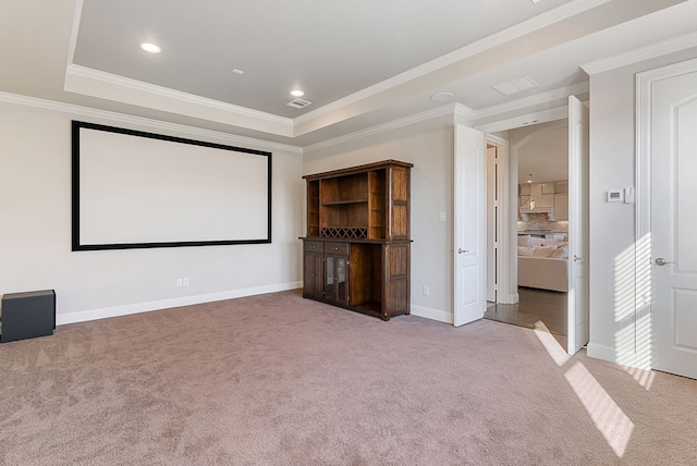 cinema room with a tray ceiling, crown molding, and carpet flooring