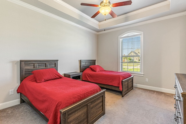 carpeted bedroom with ceiling fan, ornamental molding, and a tray ceiling