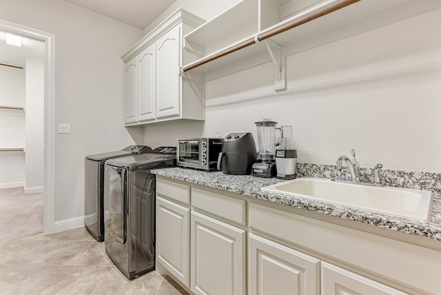 washroom with cabinets, washer and clothes dryer, and sink