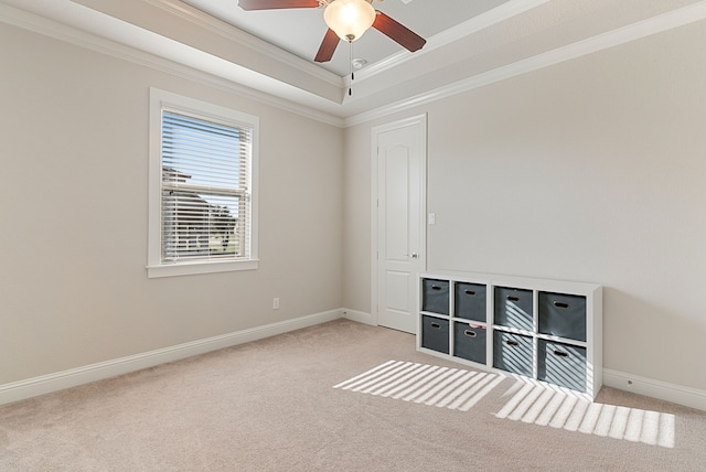 unfurnished room featuring ceiling fan, light colored carpet, a tray ceiling, and crown molding