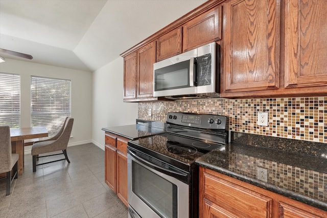 kitchen featuring backsplash, dark stone countertops, lofted ceiling, and stainless steel appliances