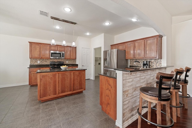 kitchen featuring backsplash, kitchen peninsula, stainless steel appliances, and decorative light fixtures