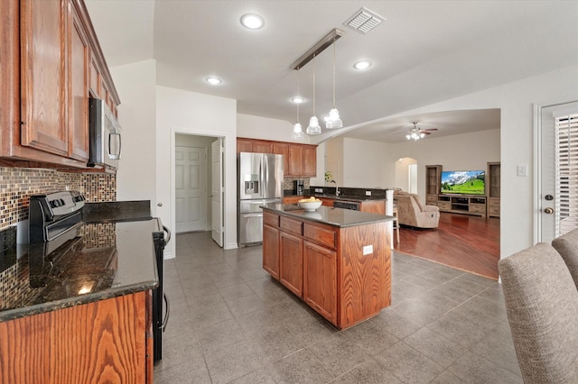 kitchen featuring a center island, ceiling fan with notable chandelier, hanging light fixtures, decorative backsplash, and stainless steel appliances