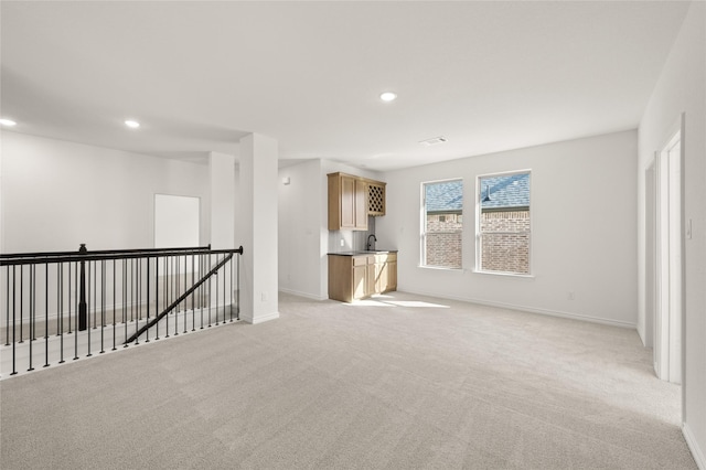 unfurnished living room with light colored carpet and sink