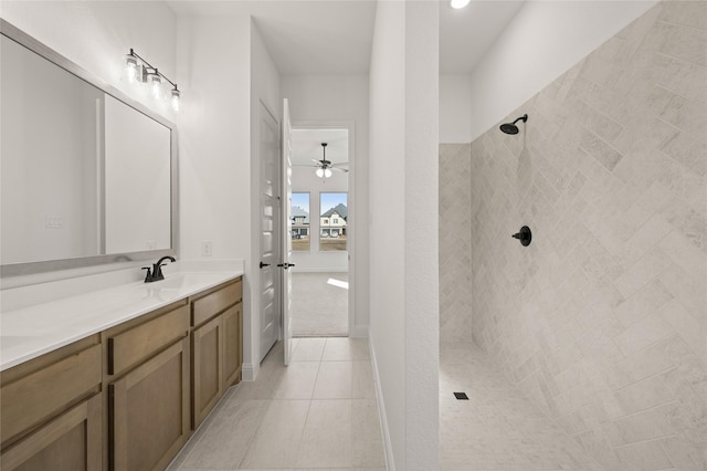 bathroom with ceiling fan, tile patterned flooring, a tile shower, and vanity