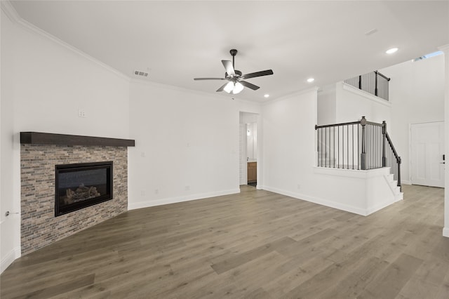 unfurnished living room featuring ceiling fan, a fireplace, ornamental molding, and hardwood / wood-style flooring