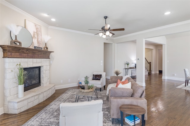 living room featuring dark hardwood / wood-style flooring, ceiling fan, a fireplace, and crown molding