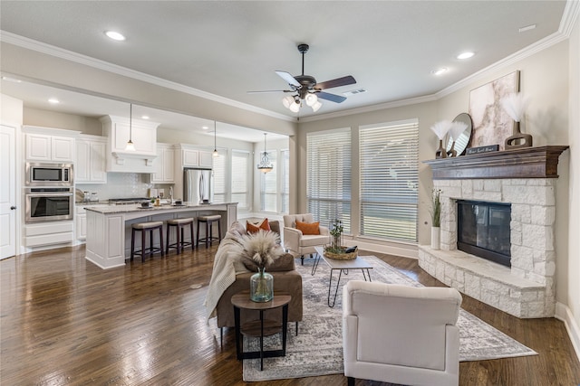 living room with ceiling fan, sink, dark hardwood / wood-style flooring, crown molding, and a fireplace