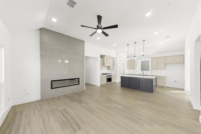 unfurnished living room featuring light wood finished floors, visible vents, lofted ceiling, a fireplace, and recessed lighting