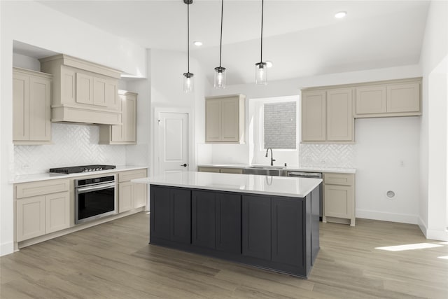 kitchen featuring light wood finished floors, a center island, light countertops, stainless steel appliances, and a sink