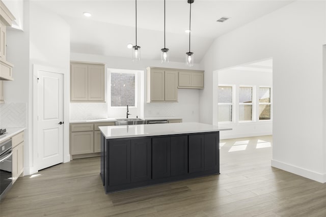kitchen with a center island, vaulted ceiling, a sink, and light wood finished floors