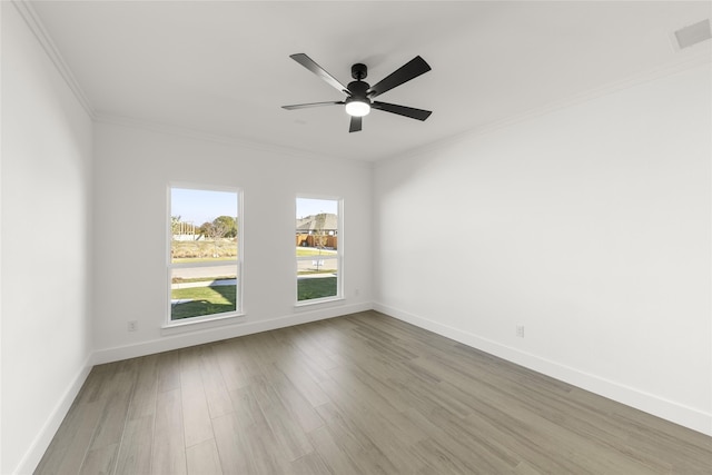 empty room with a ceiling fan, crown molding, baseboards, and wood finished floors