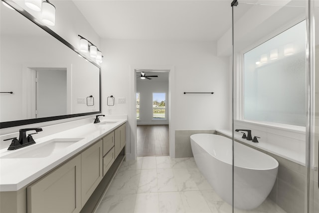 bathroom featuring double vanity, marble finish floor, a sink, and a soaking tub