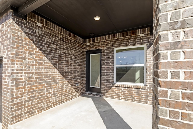 doorway to property featuring a patio and brick siding