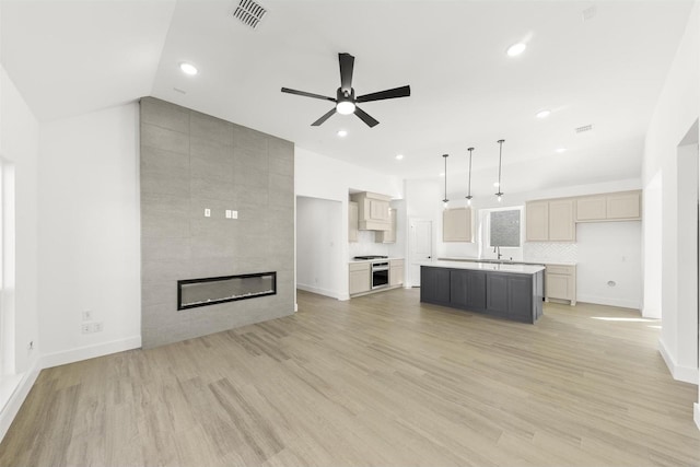 unfurnished living room with recessed lighting, visible vents, a tiled fireplace, vaulted ceiling, and light wood-type flooring